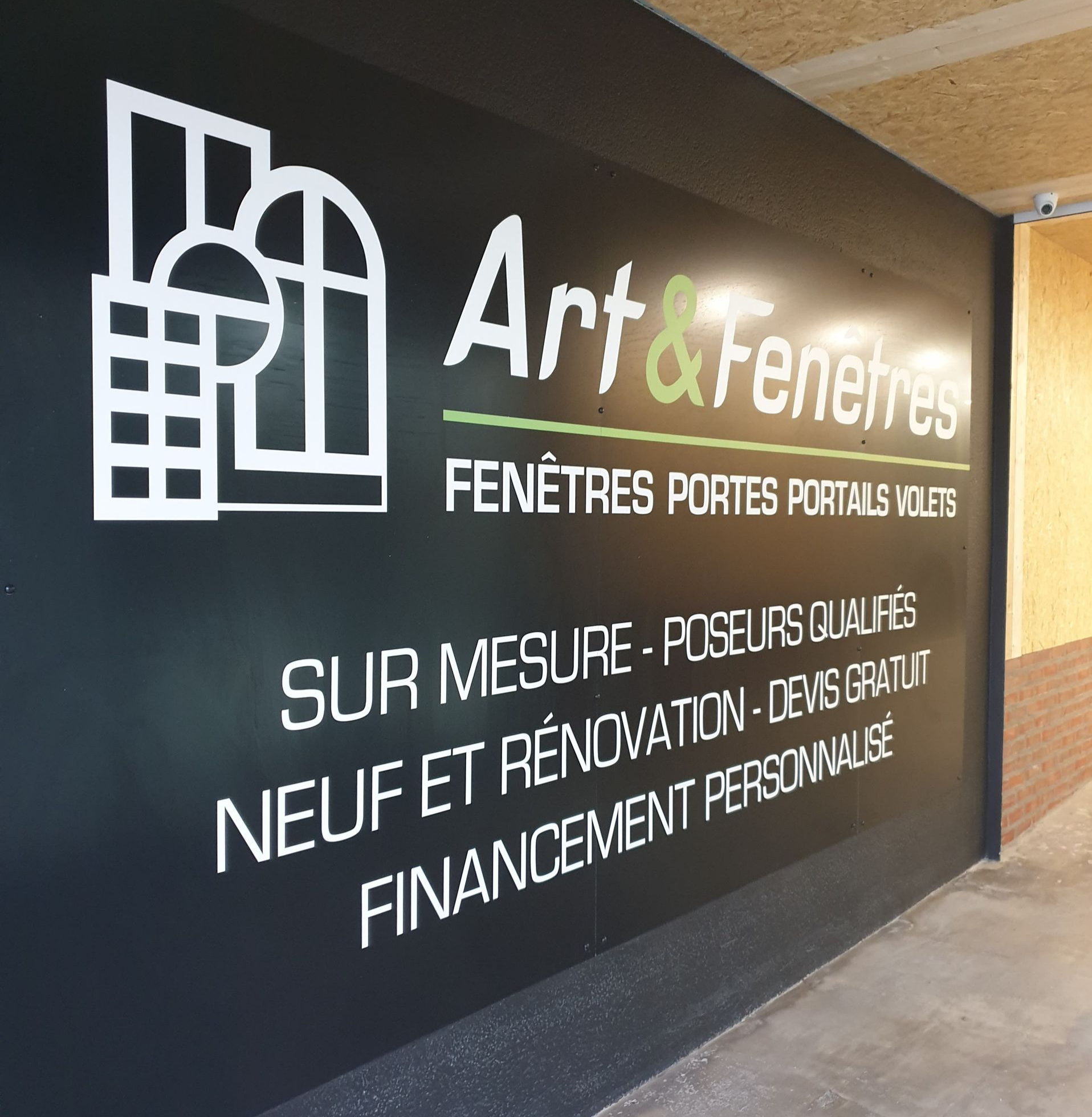 Entrée aux murs de pierre avec une porte grise, une petite table et du bois de chauffage empilé.