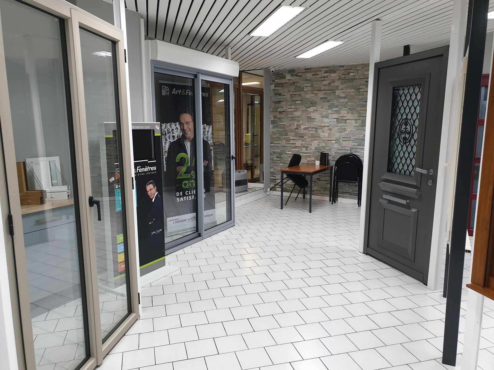 Salle d'exposition avec portes et vitrines d'exposition; intérieur gris et blanc.