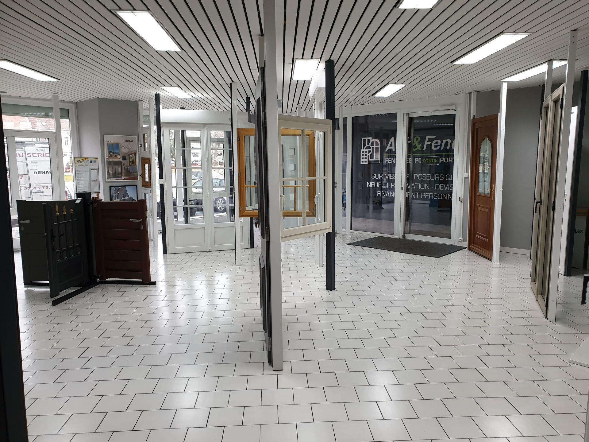 Salle d'exposition intérieure présentant portes et fenêtres, sol carrelé blanc, éclairage zénithal.