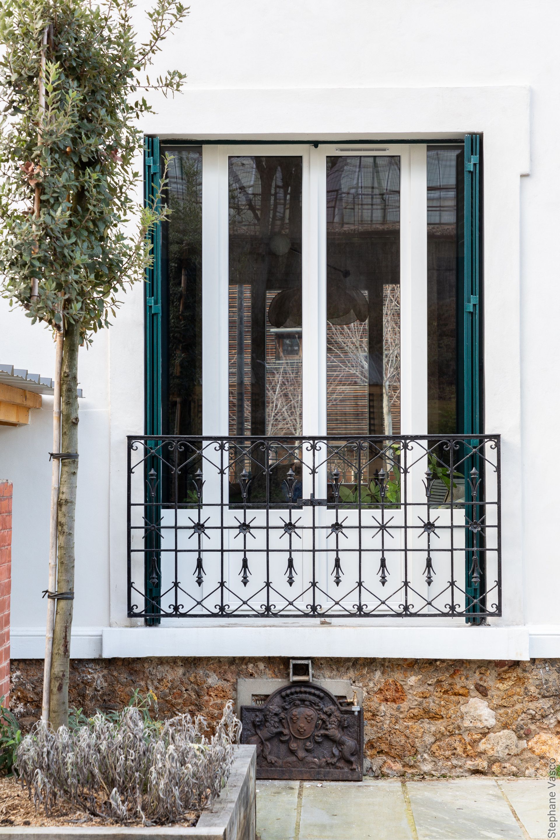 Façade blanche avec balcon et volets verts.