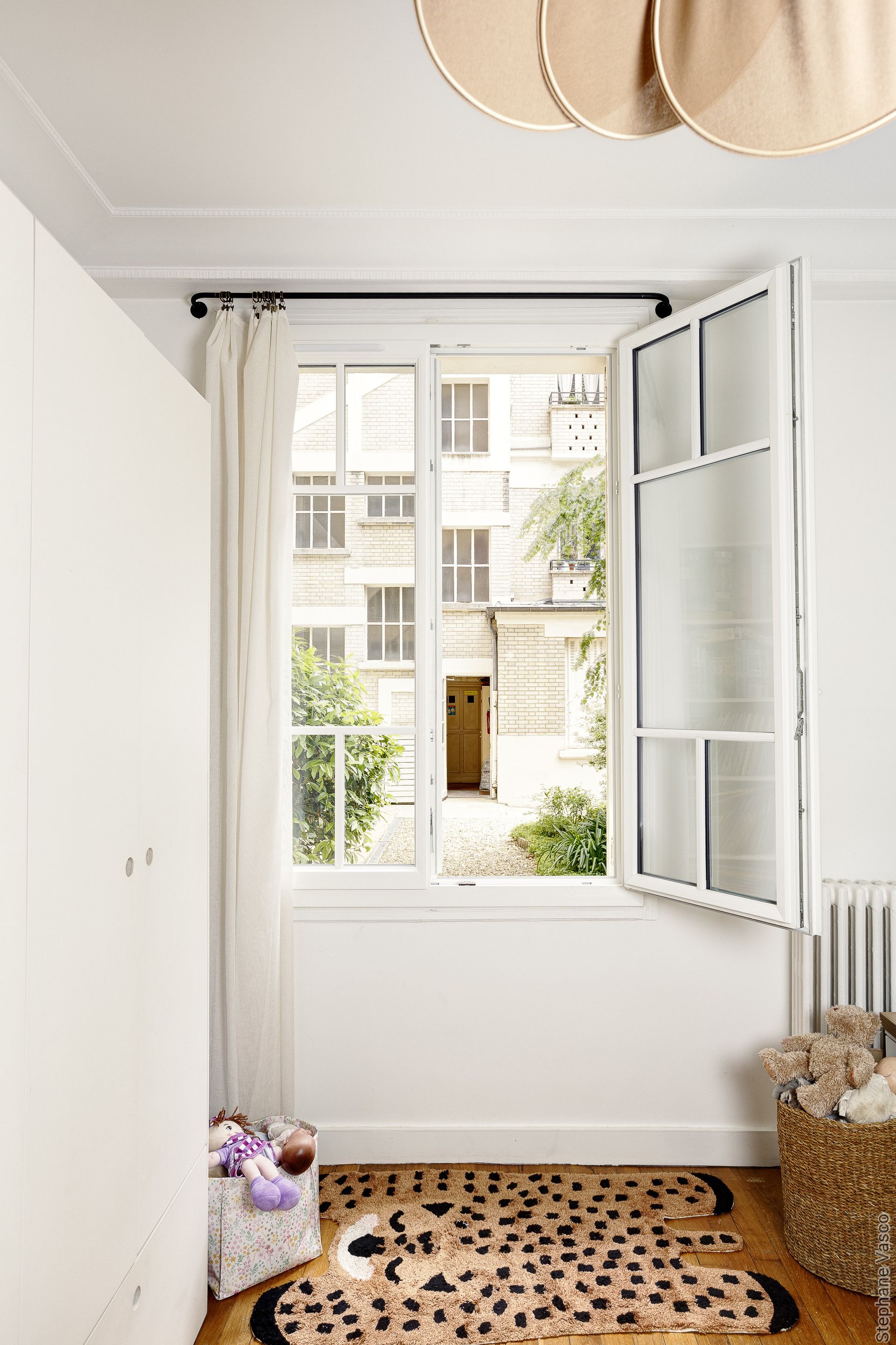 Chambre aux murs blancs avec fenêtre ouverte.