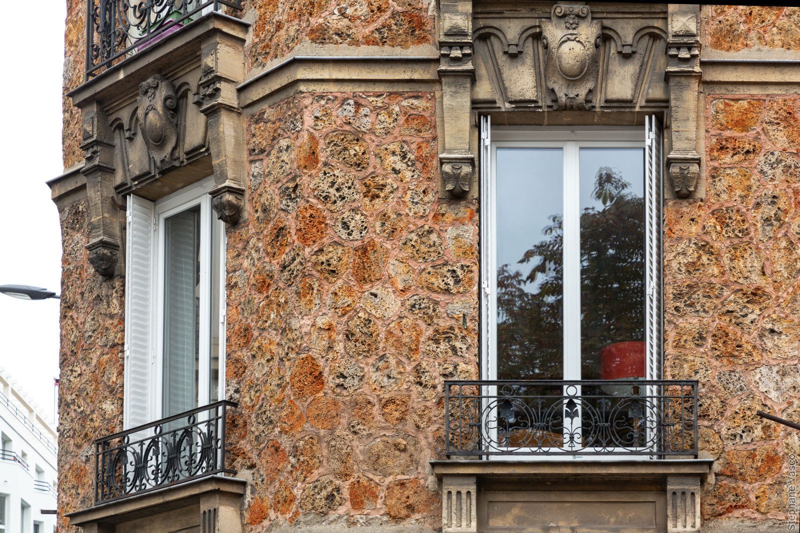 Façade d'un immeuble en pierre avec des encadrements de fenêtres et des balcons ornés.