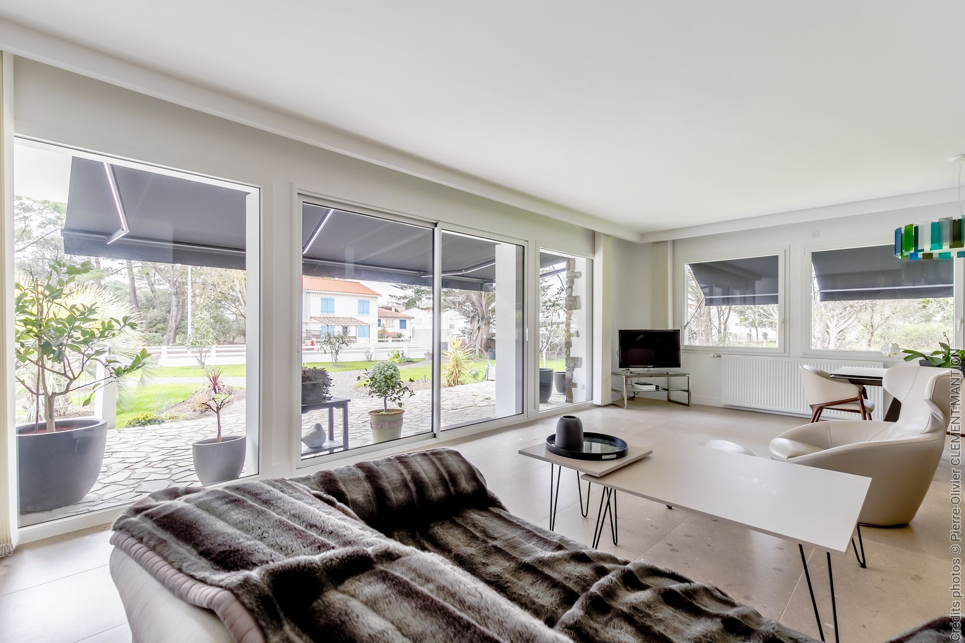 Salon lumineux avec de grandes fenêtres donnant sur la cour.