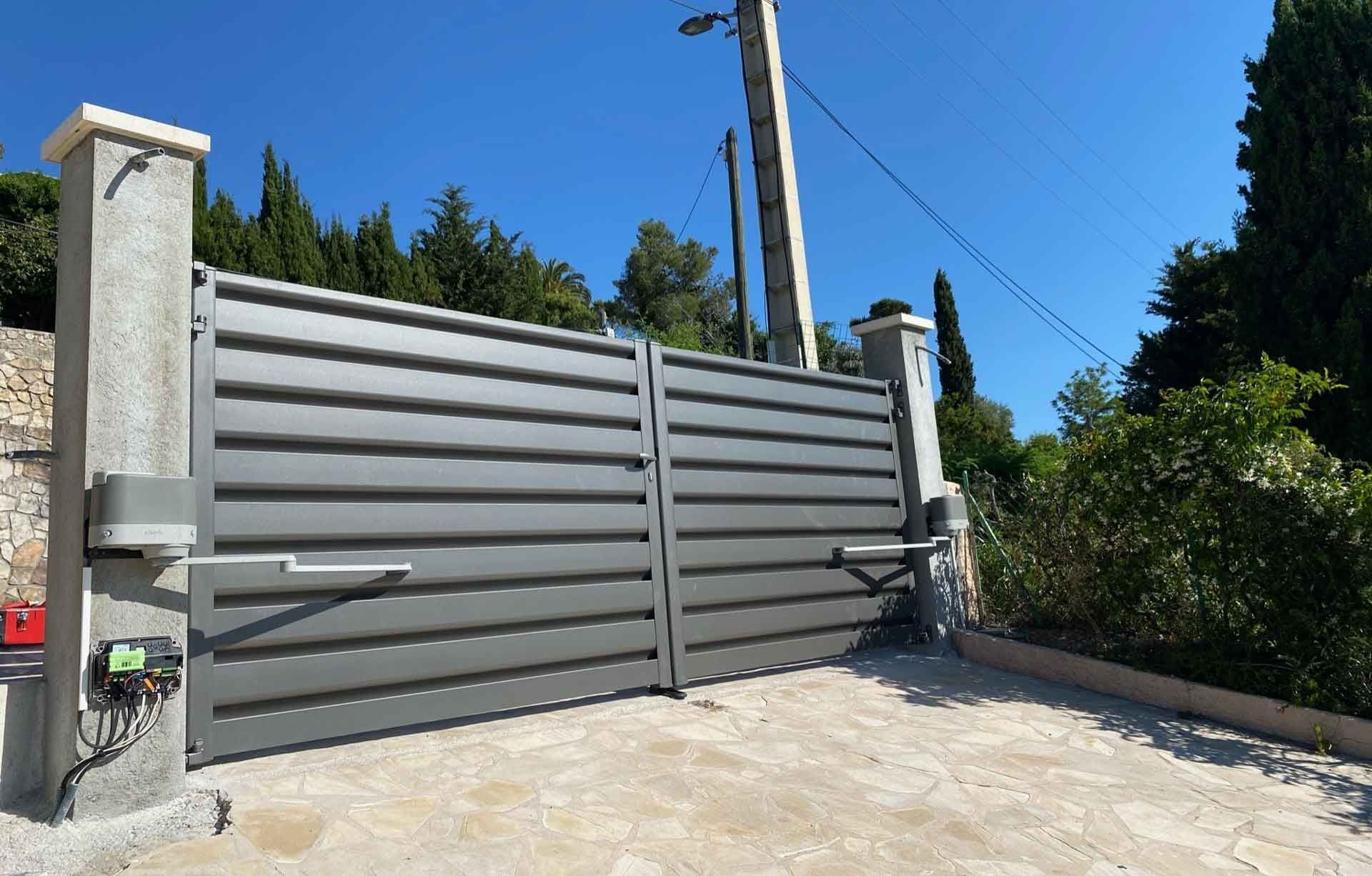 Portail battant motorisé gris.