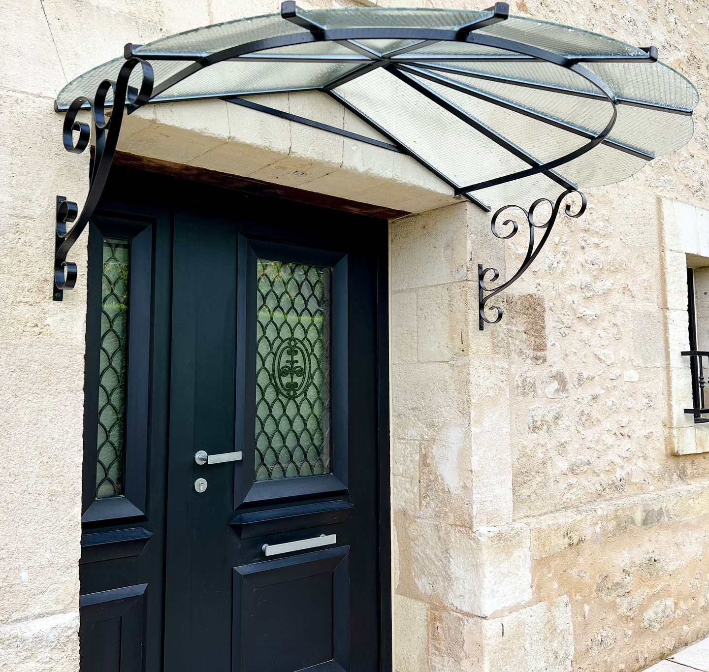 Porte d'entrée noire avec une marquise au-dessus.