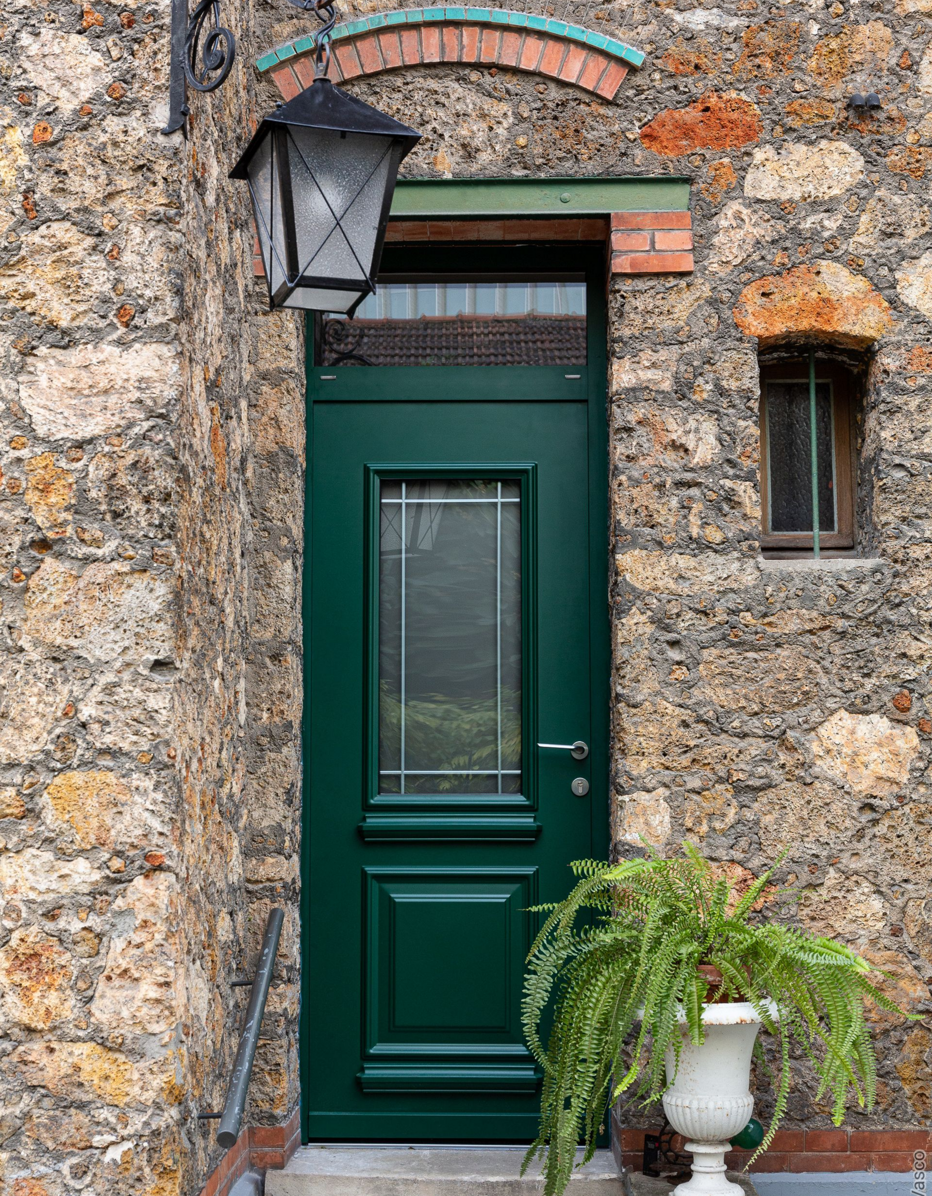 Entrée d'une maison avec une porte verte et un escalier devant.