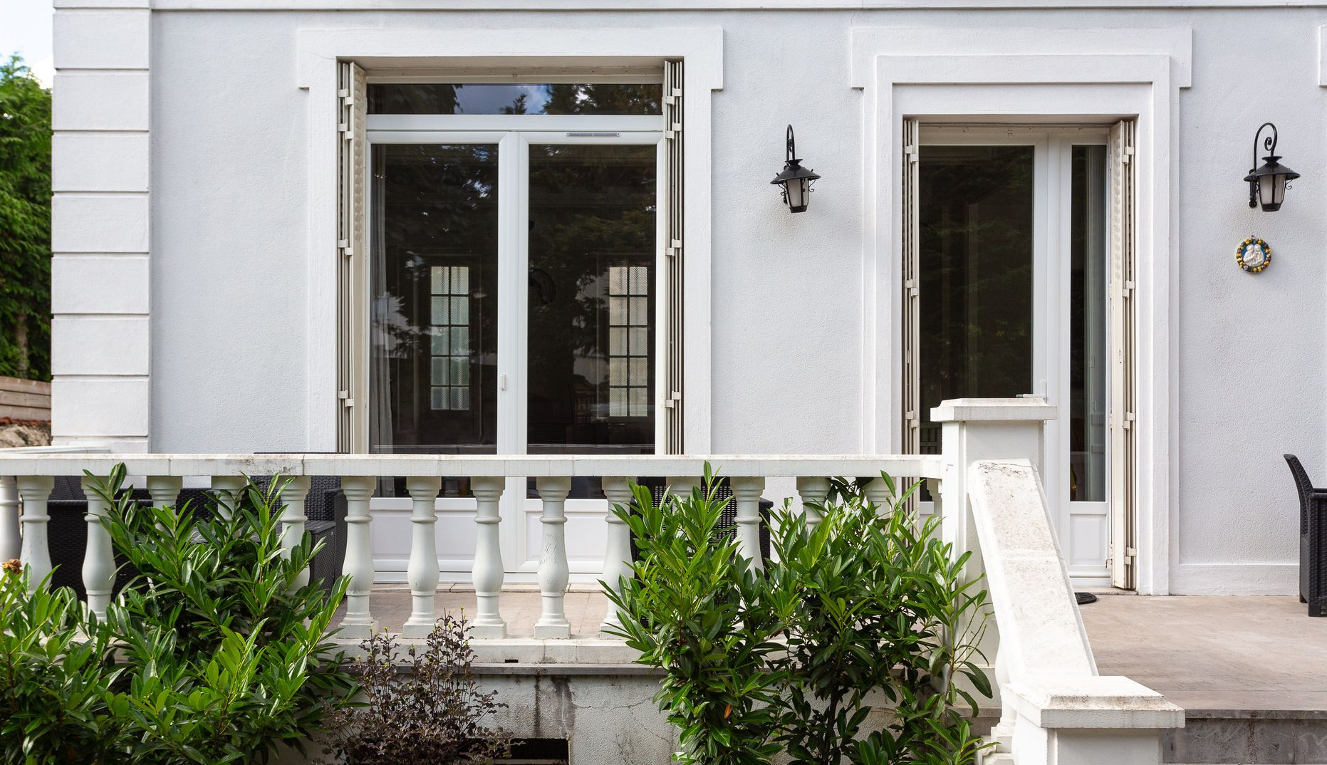 Façade d'une maison blanche avec balcon, fenêtres et marches.
