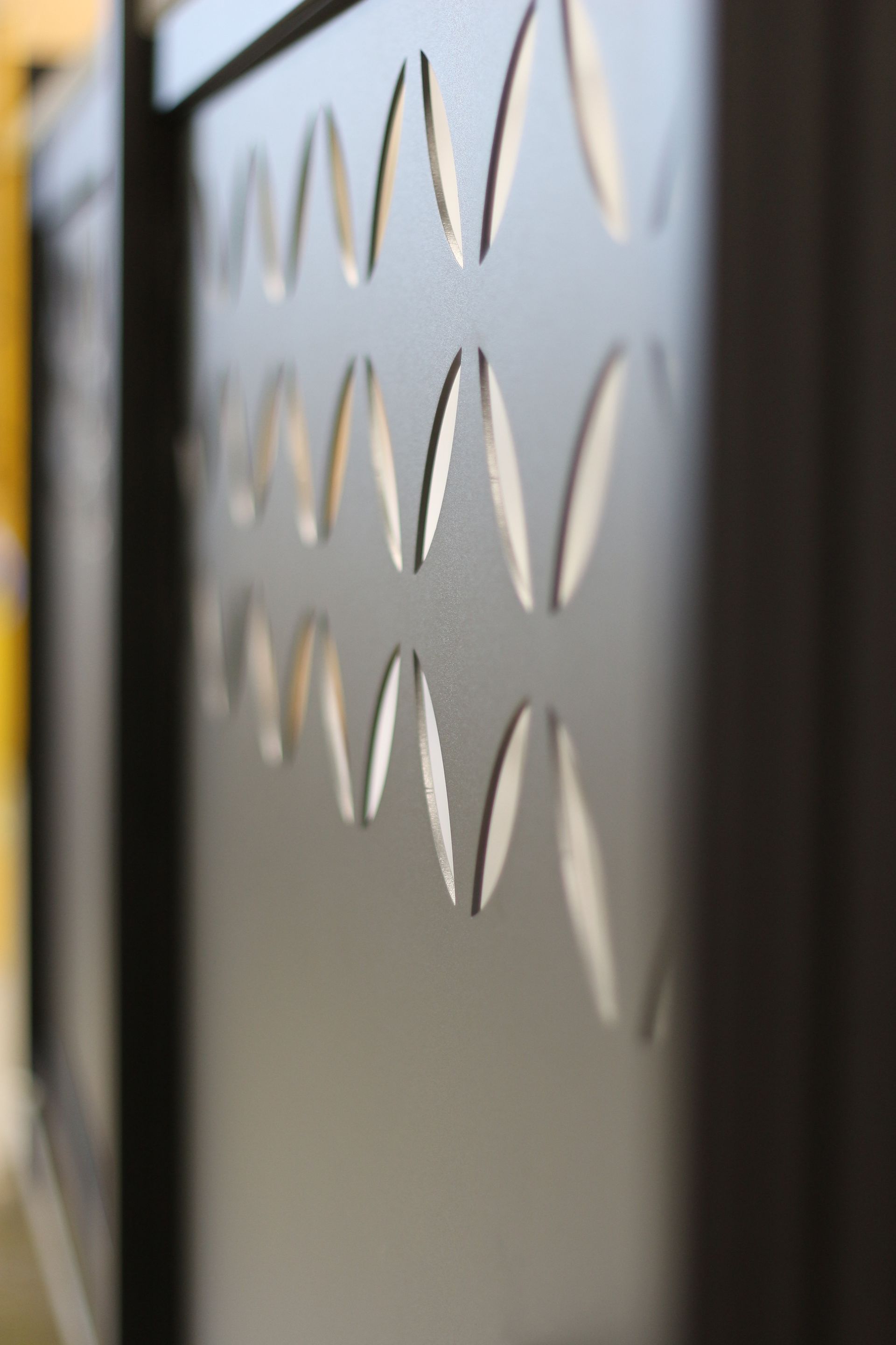 Gros plan d'un panneau métallique gris foncé avec un motif de découpes ovales, probablement pour la ventilation.