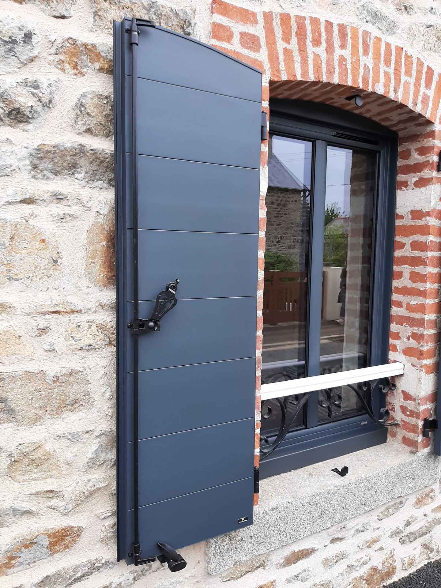 Gros plan sur le volet battant d'une maison en pierre.