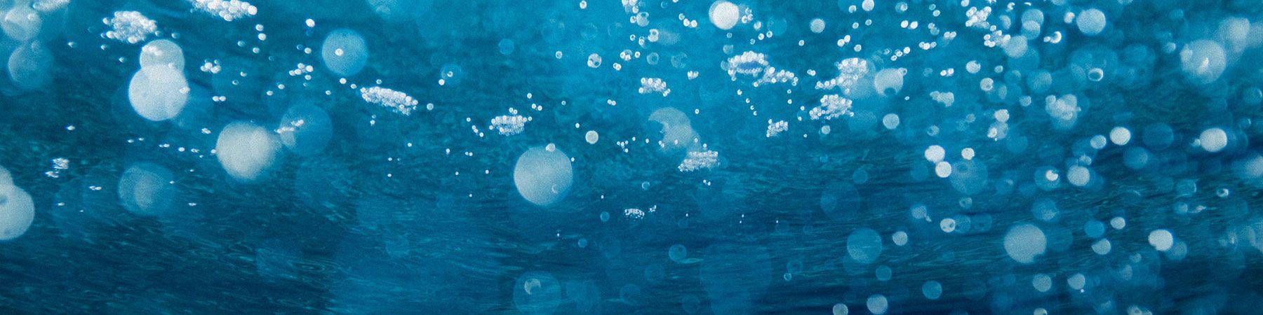 Auf blauem Hintergrund schwimmen Blasen im Wasser.