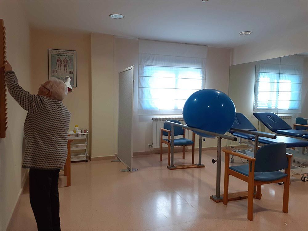 Una persona mayor se acerca a un cuadro mural en una sala de terapia.