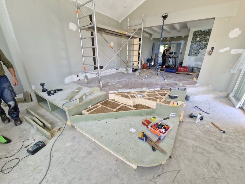 Un homme se tient debout dans une pièce avec beaucoup d'outils sur le sol.