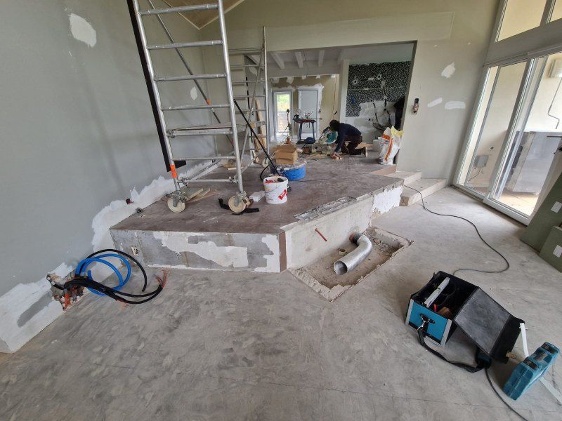 Une pièce en cours de rénovation avec un escalier en arrière-plan.