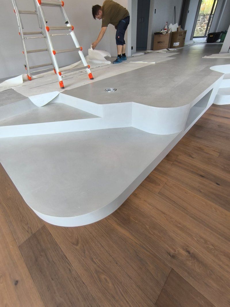 Un homme est debout sur un plancher en bois à côté d'une échelle.