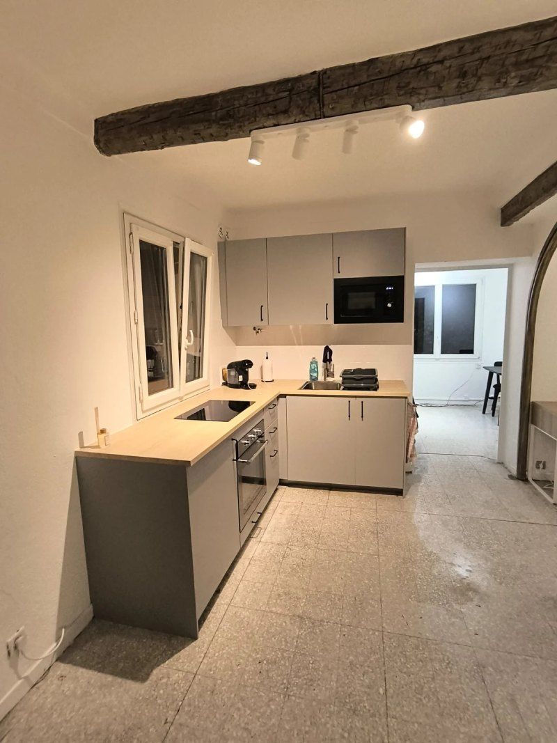 Une cuisine avec des armoires blanches, un évier et un micro-ondes.