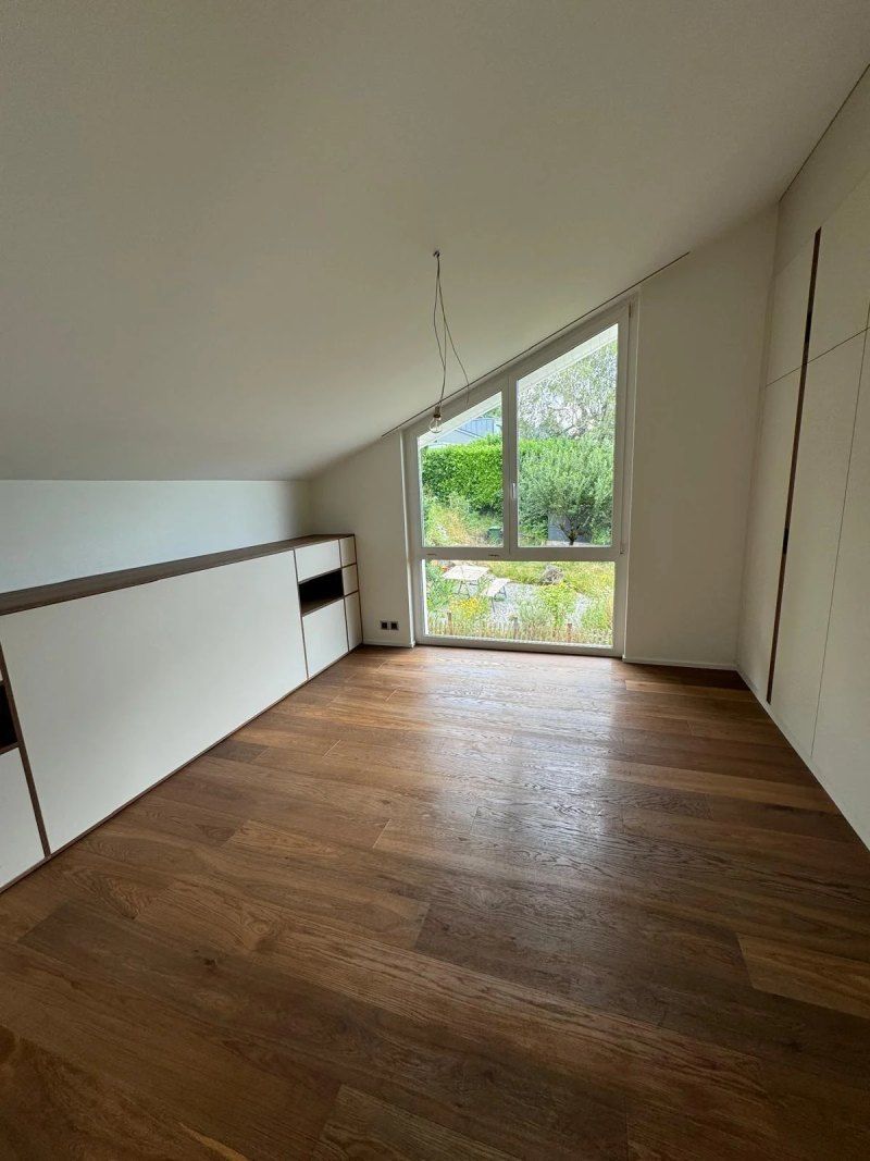 Une pièce vide avec un plancher en bois et une grande fenêtre.