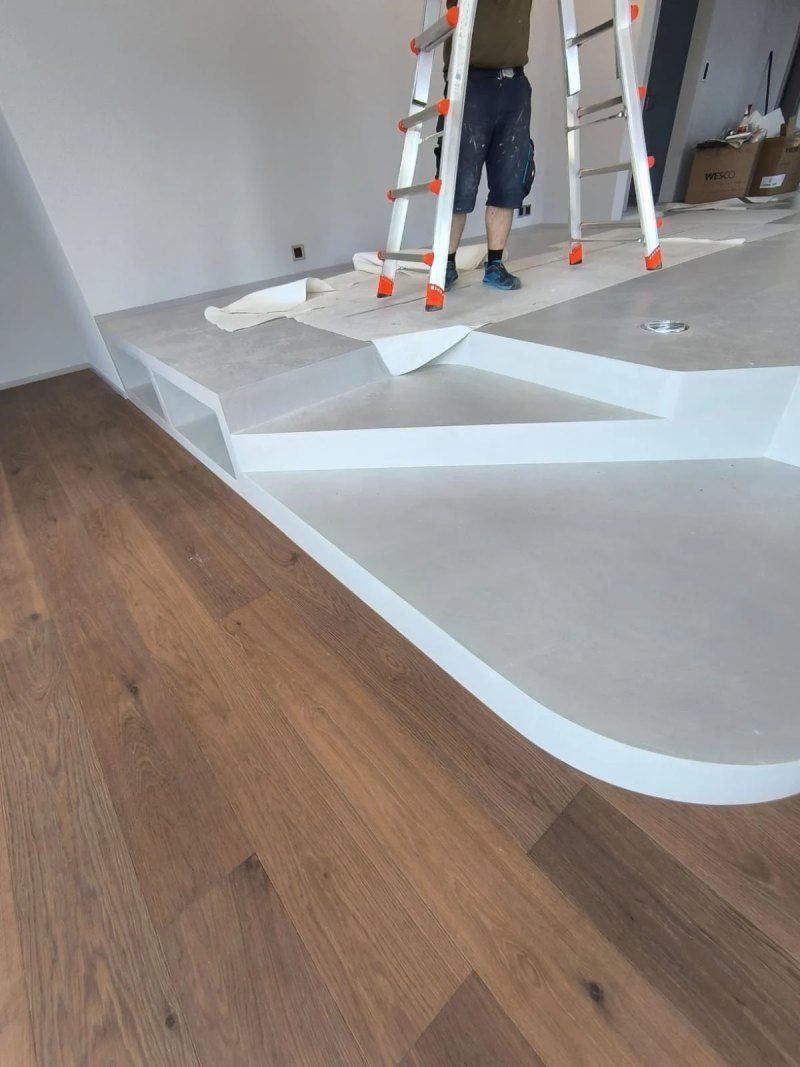 Un homme est debout sur une échelle dans une pièce avec un plancher en bois.