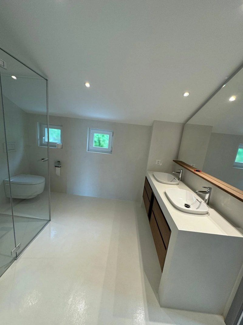 Une salle de bain avec deux lavabos, un WC et un grand miroir.