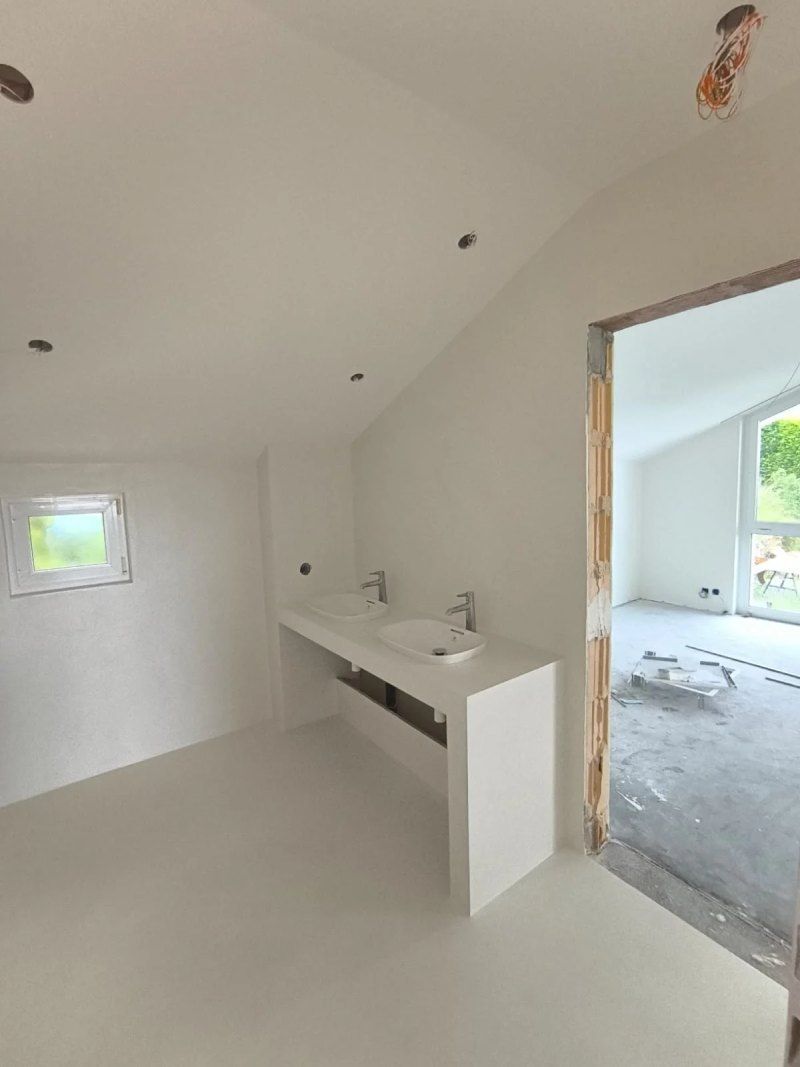 Une salle de bain avec deux lavabos et une fenêtre dans une maison en construction.