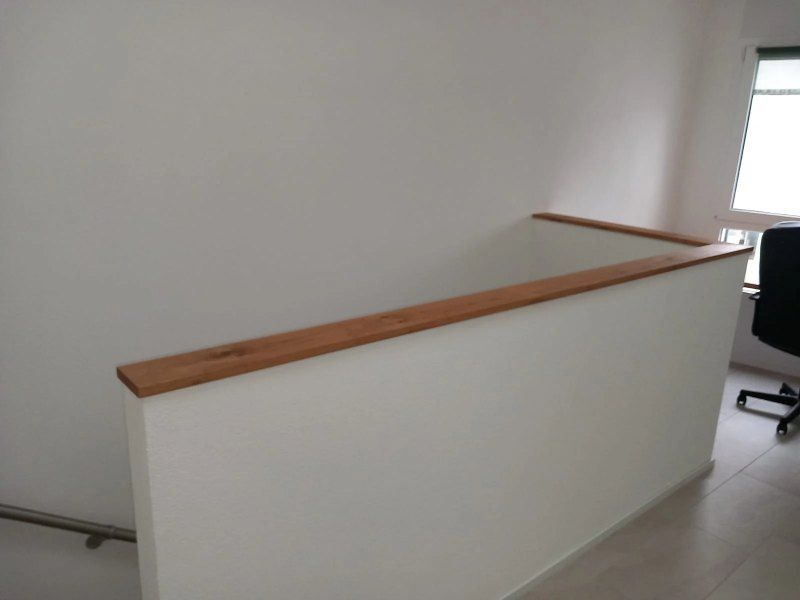 Un mur blanc avec une balustrade en bois et une chaise dans une pièce.