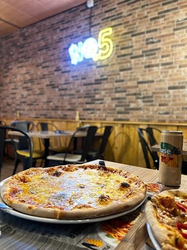 Une pizza et une canette de soda sont sur une table dans un restaurant.