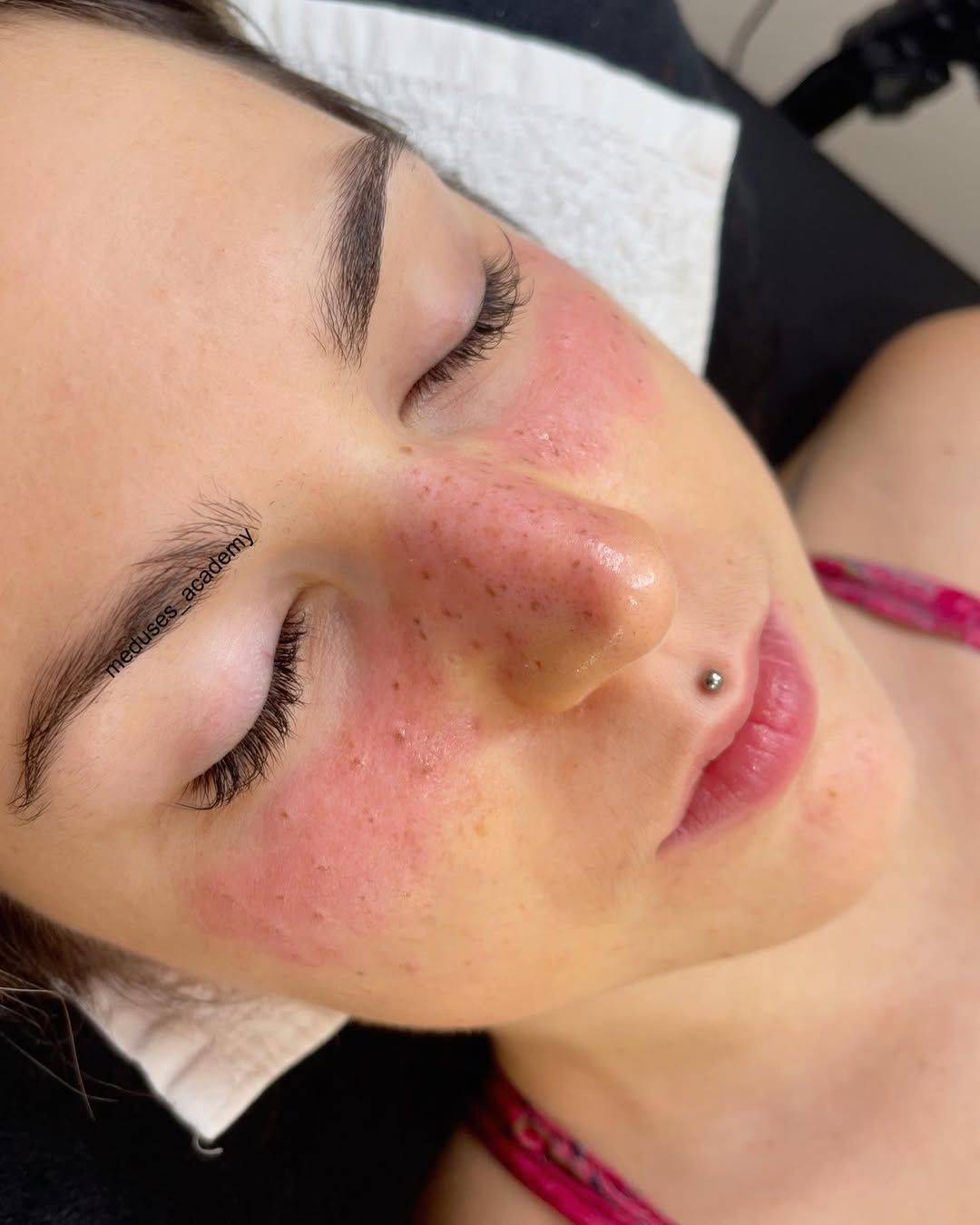 Primer plano de una persona con los ojos cerrados, las mejillas sonrojadas y un piercing en la nariz