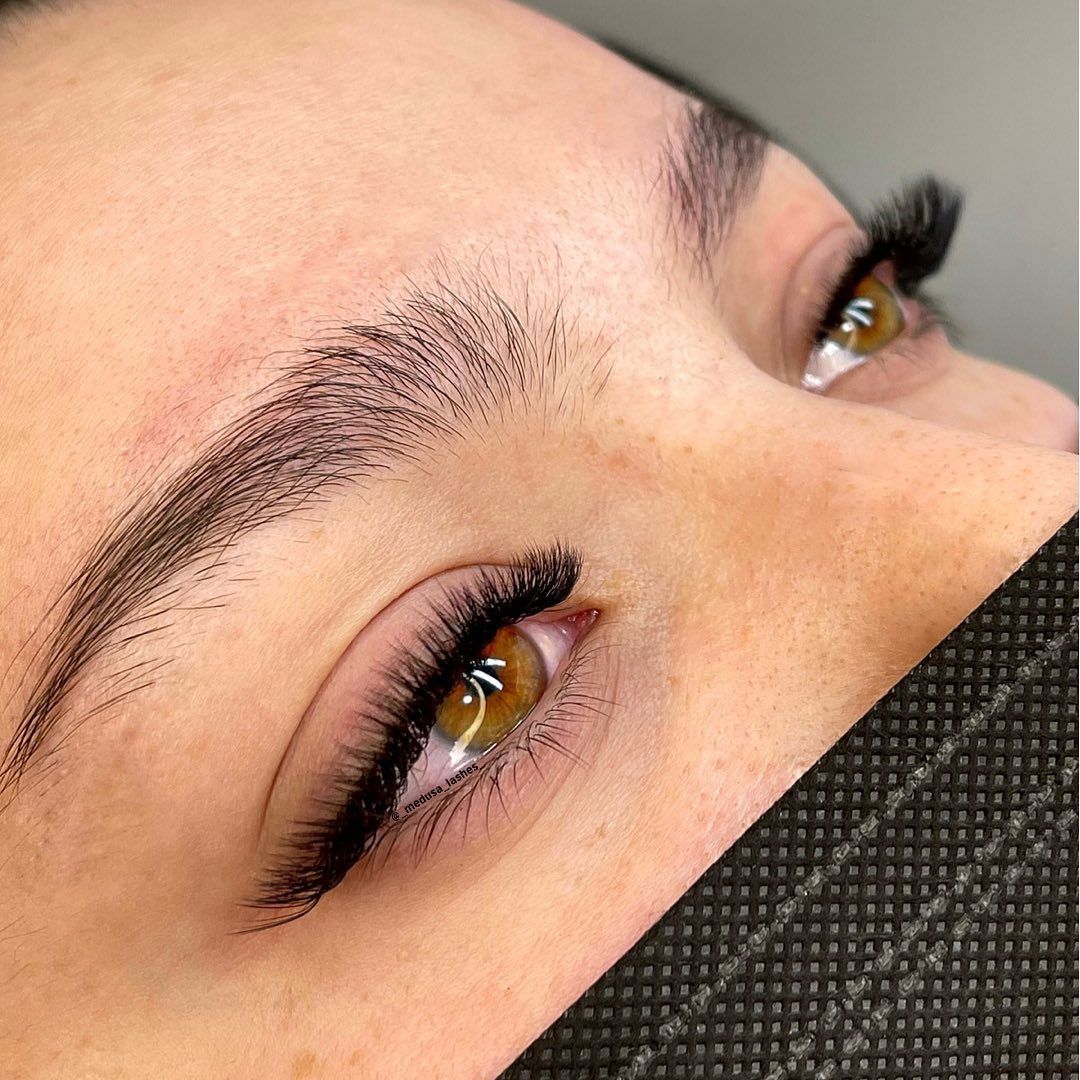 Primer plano de unos ojos con largas pestañas y cejas bien definidas, parcialmente cubiertos por una mascarilla negra.