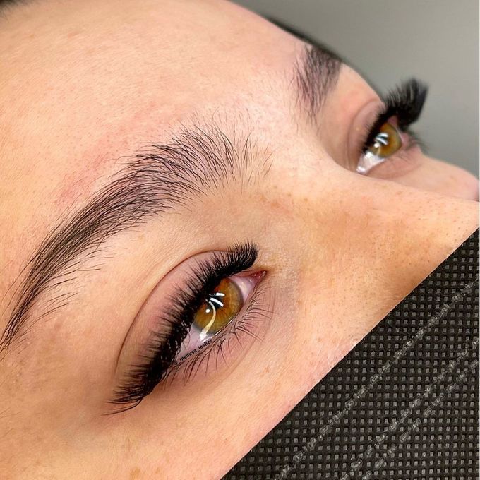 Primer plano de unos ojos con largas pestañas y cejas bien definidas, parcialmente cubiertos por una mascarilla negra.