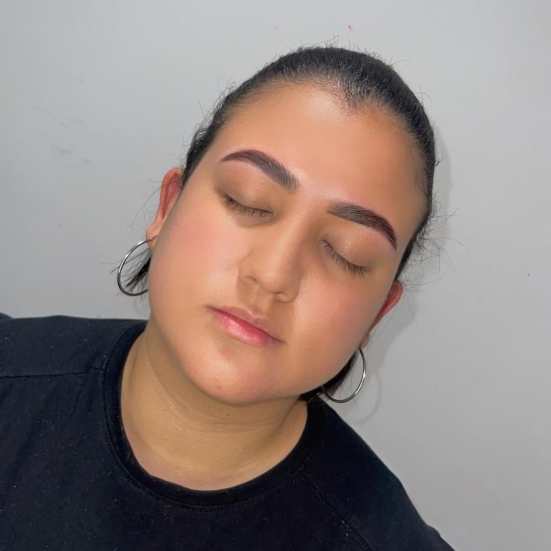 Primer plano de una persona con los ojos cerrados, vestida con una camisa negra y pendientes de aro