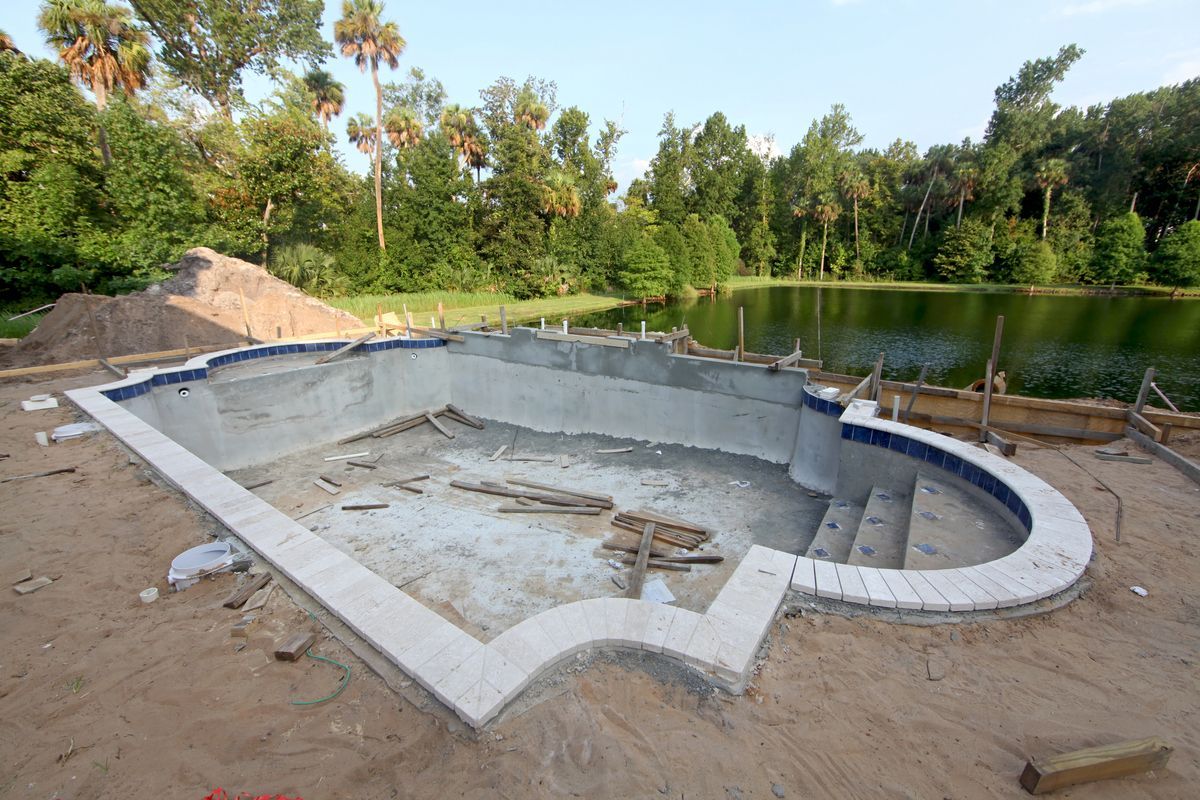 Piscina vacía con tableros de madera al lado de un lago