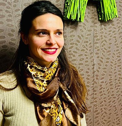 Una mujer sonríe delante de una letra 