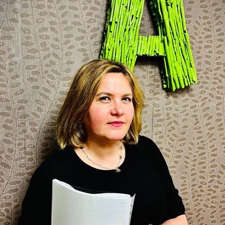 Una mujer está parada frente a una pared con una letra a verde escrita en ella.