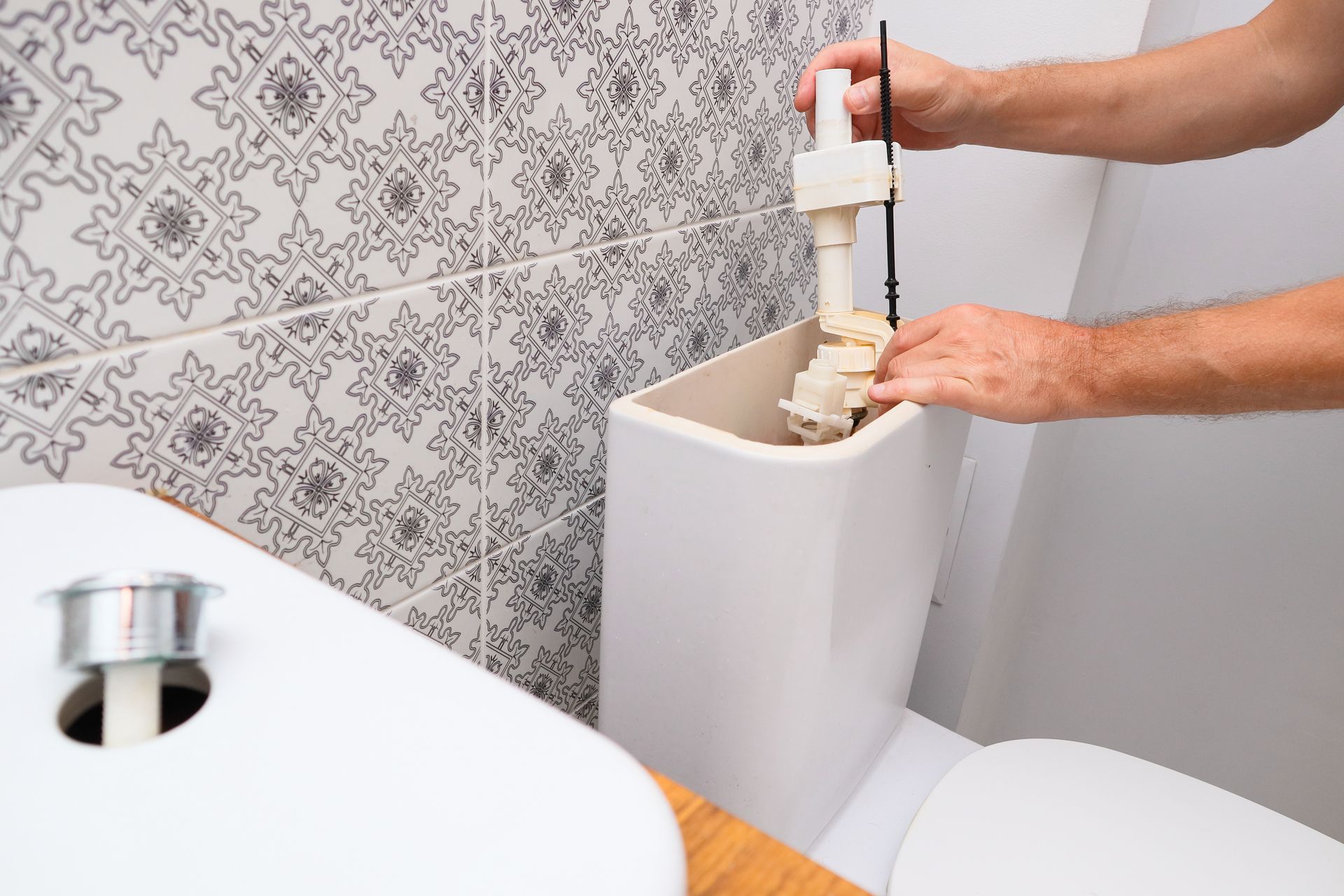 Installation d'un robinet de remplissage de réservoir de toilettes dans une salle de bains, les mains ajustant le dispositif.