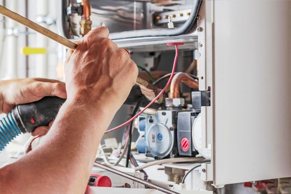 Technicien réparant le câblage d'une chaudière.