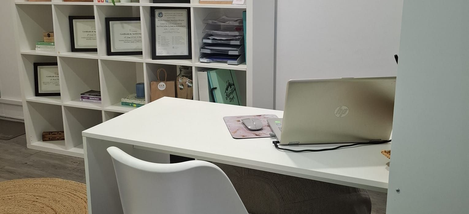 Escritorio blanco con un portátil abierto y una silla en una oficina o área de estudio ordenada