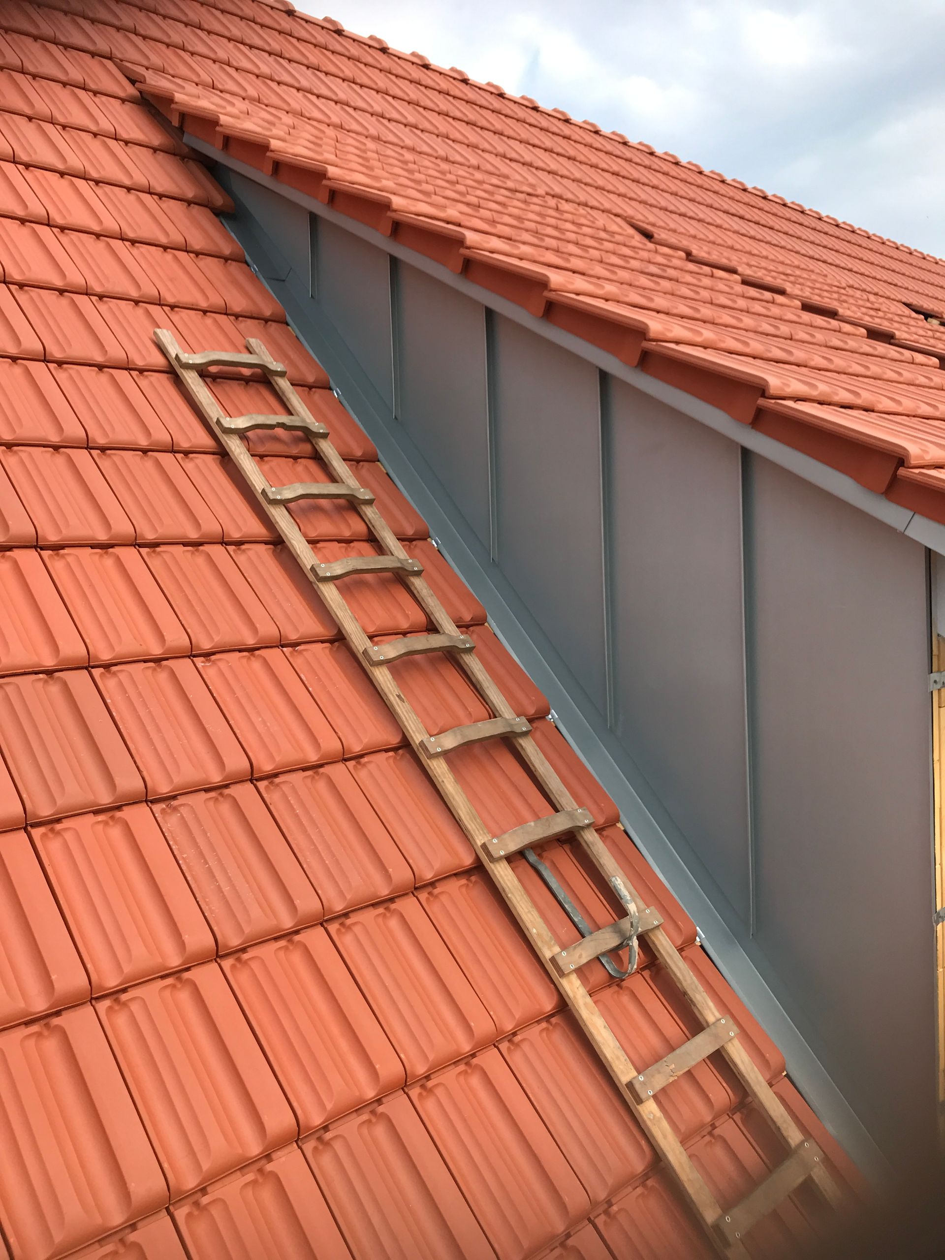 Eine Person schraubt mit einem gelben Bohrer im Freien Paneele an eine Konstruktion.