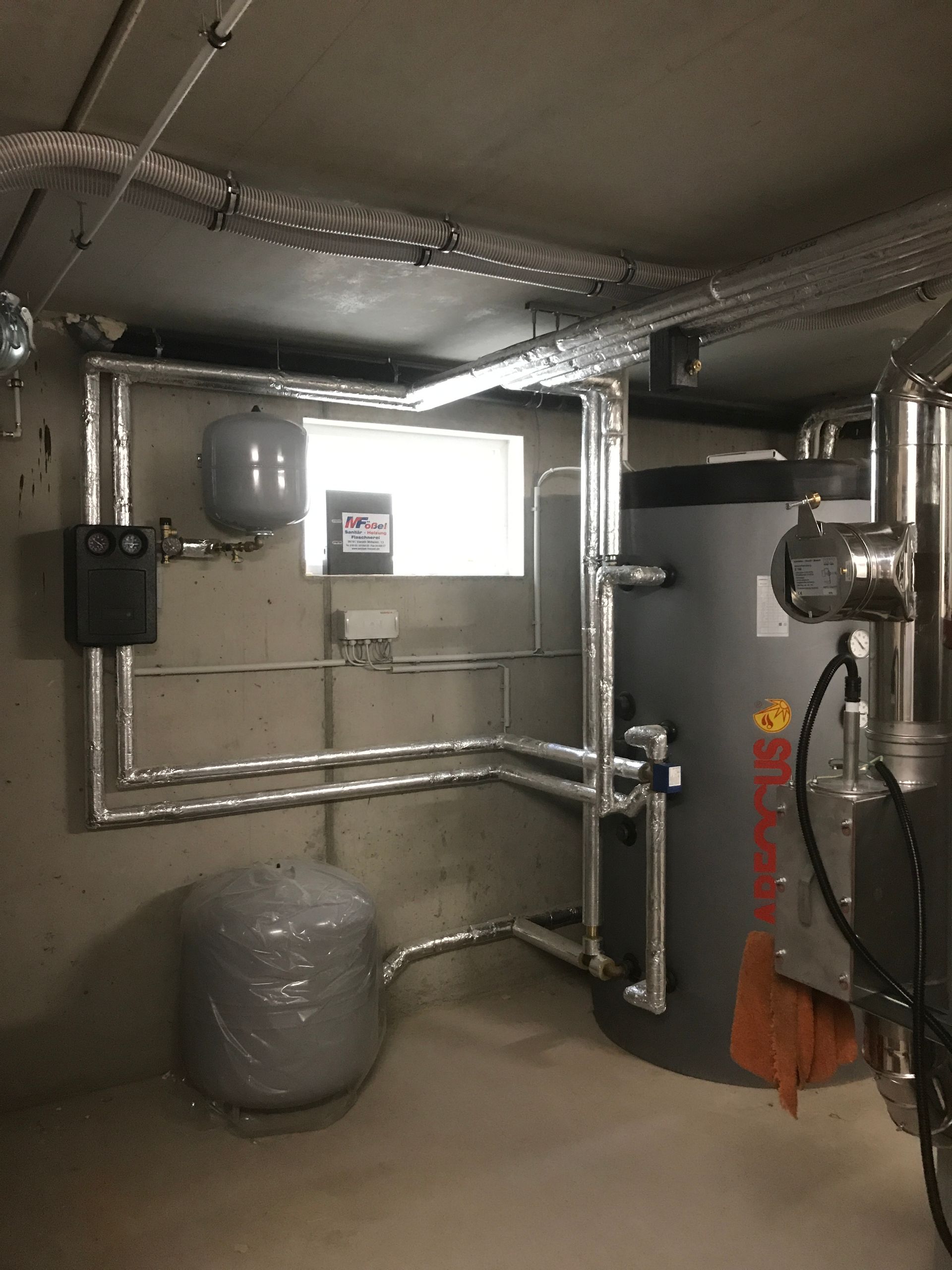 Eine Hand repariert mit einer Zange und Wassersprühung ein undichtes Rohr.