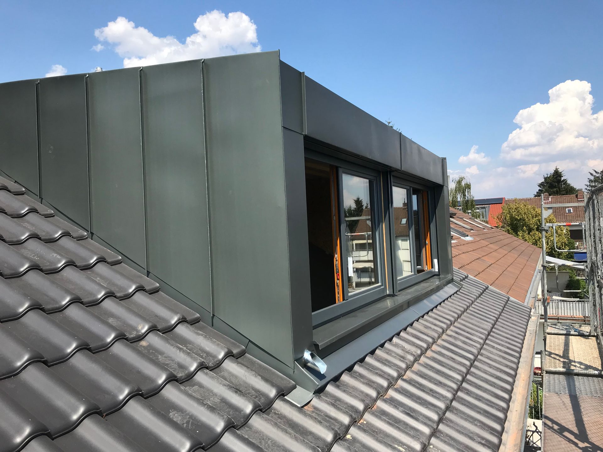 Eine Person benutzt einen orangefarbenen Schraubenschlüssel, um ein Rohr unter einem Waschbecken im Badezimmer festzuziehen.