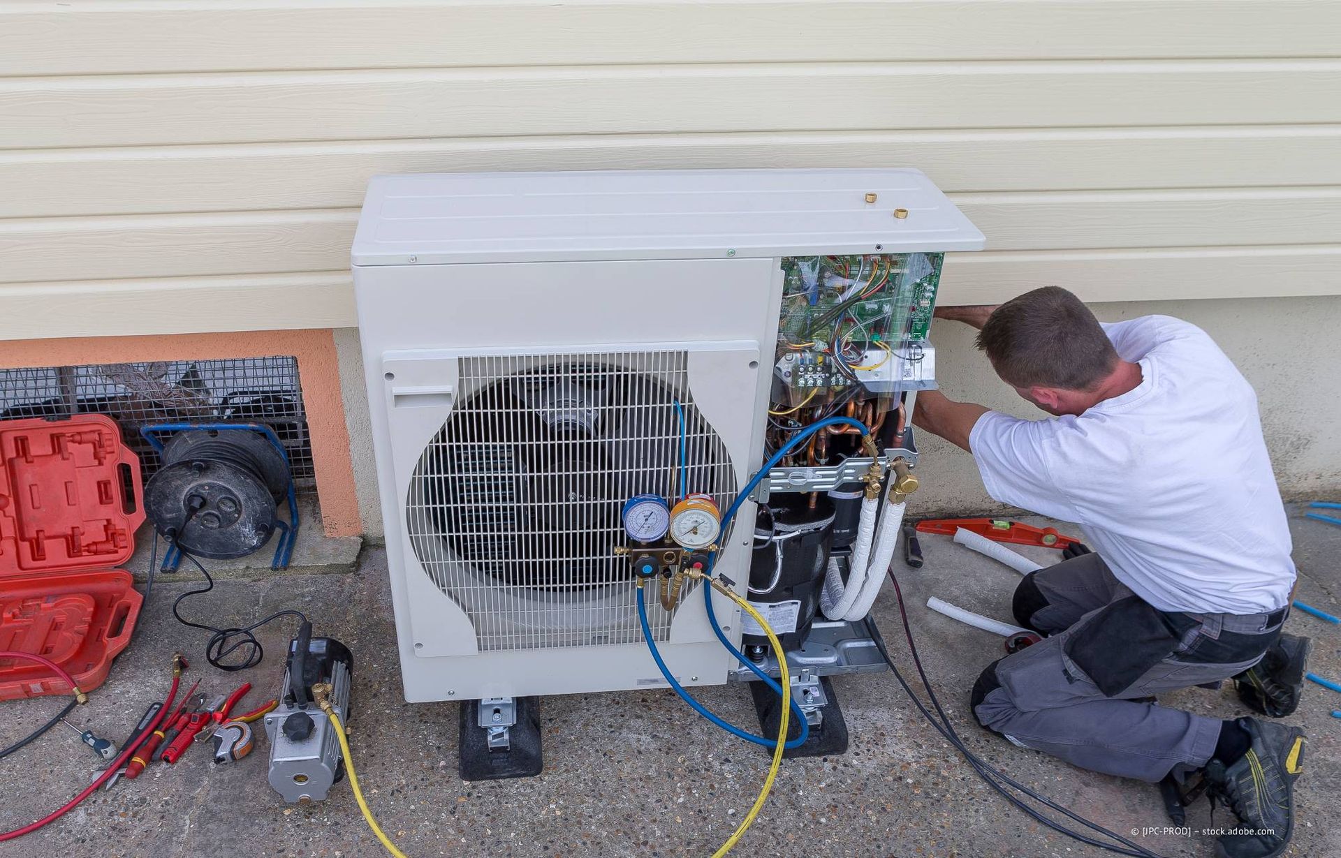 Klimatechniker arbeitet an einer Klimaanlage außerhalb eines Gebäudes.