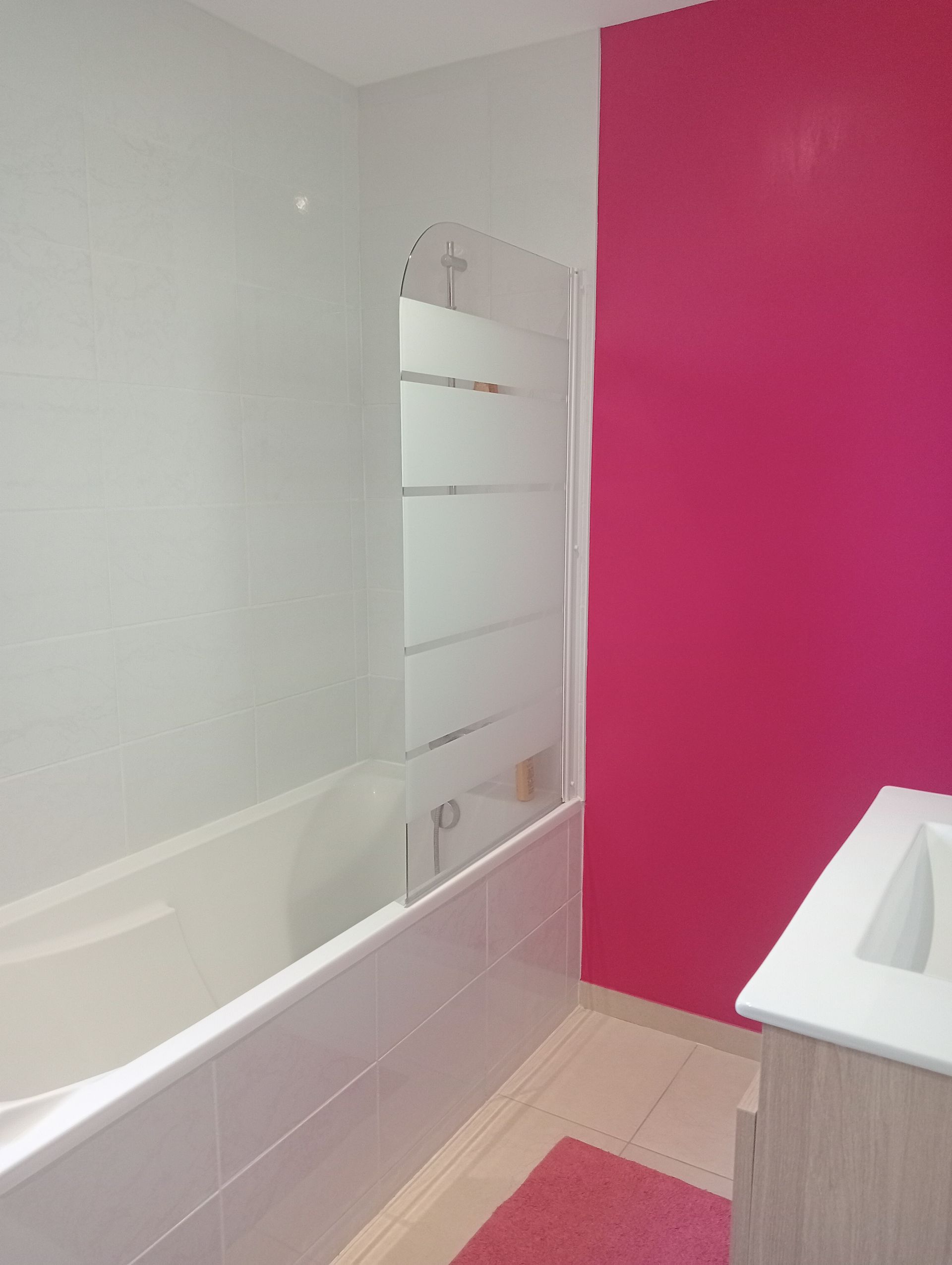 Une baignoire avec une vitre dans une salle de bains rose