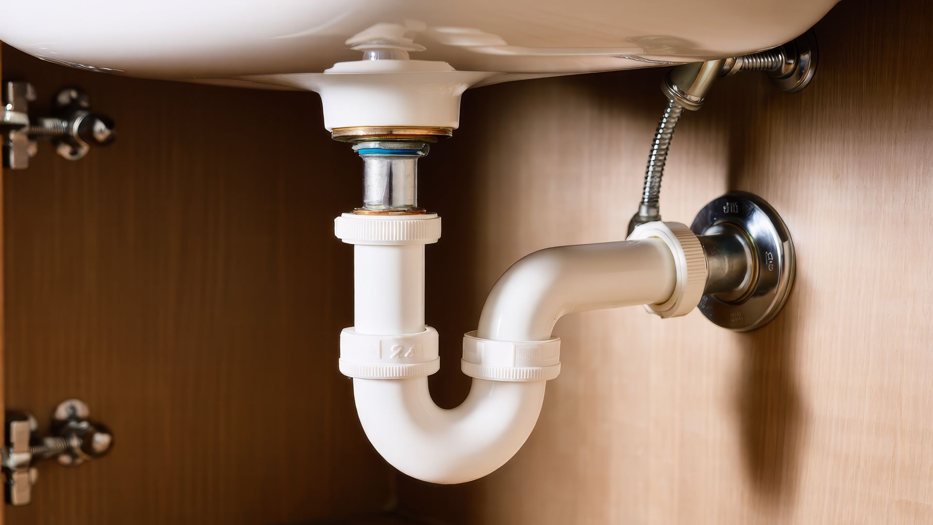 Homme réparant un siphon d’évier avec une clé à molette dans une salle de bains
