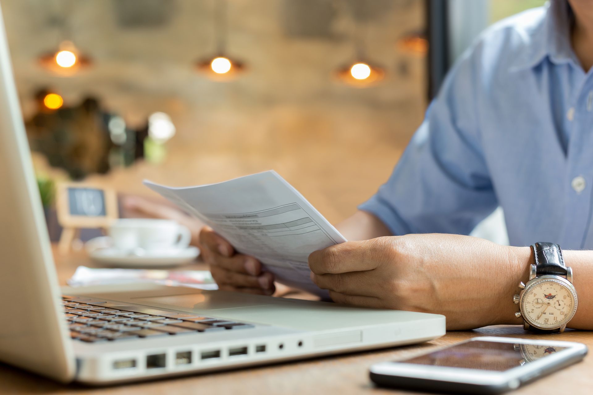 Homme qui tient un document devant un ordinateur