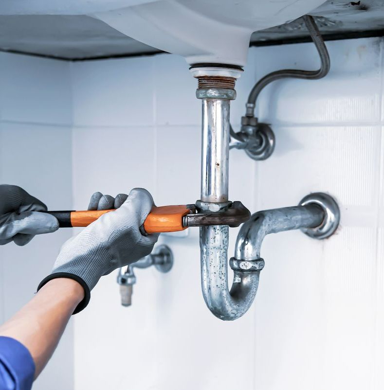 Personne en train de serrer un siphon avec une clé à molette