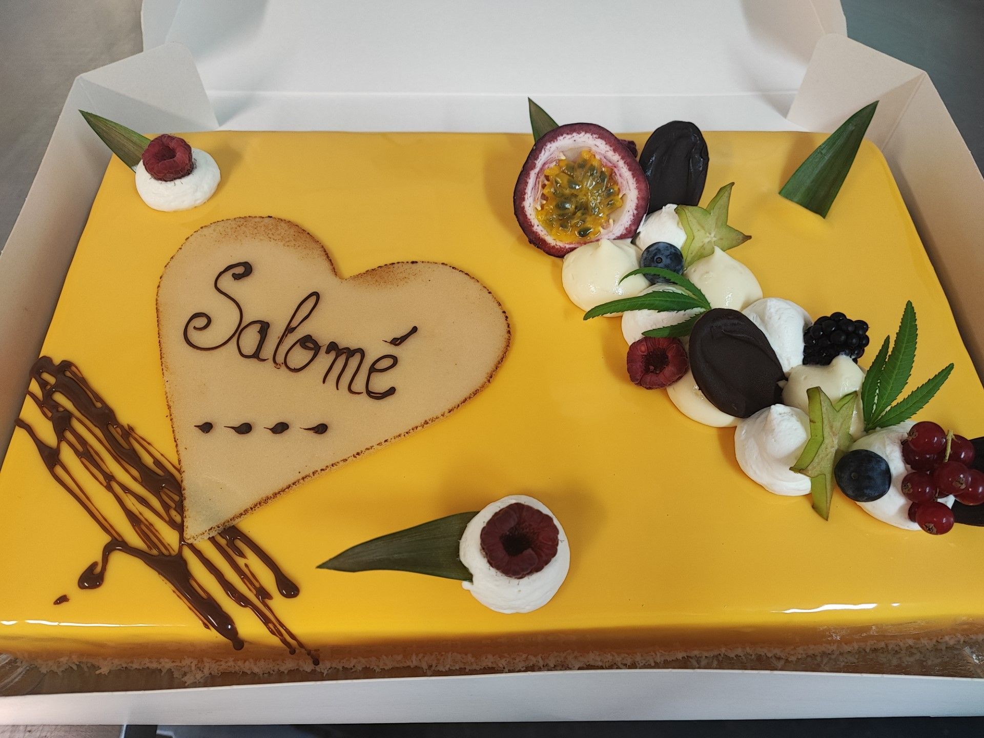 Gâteau avec glaçage jaune, décorations et cœur avec le prénom