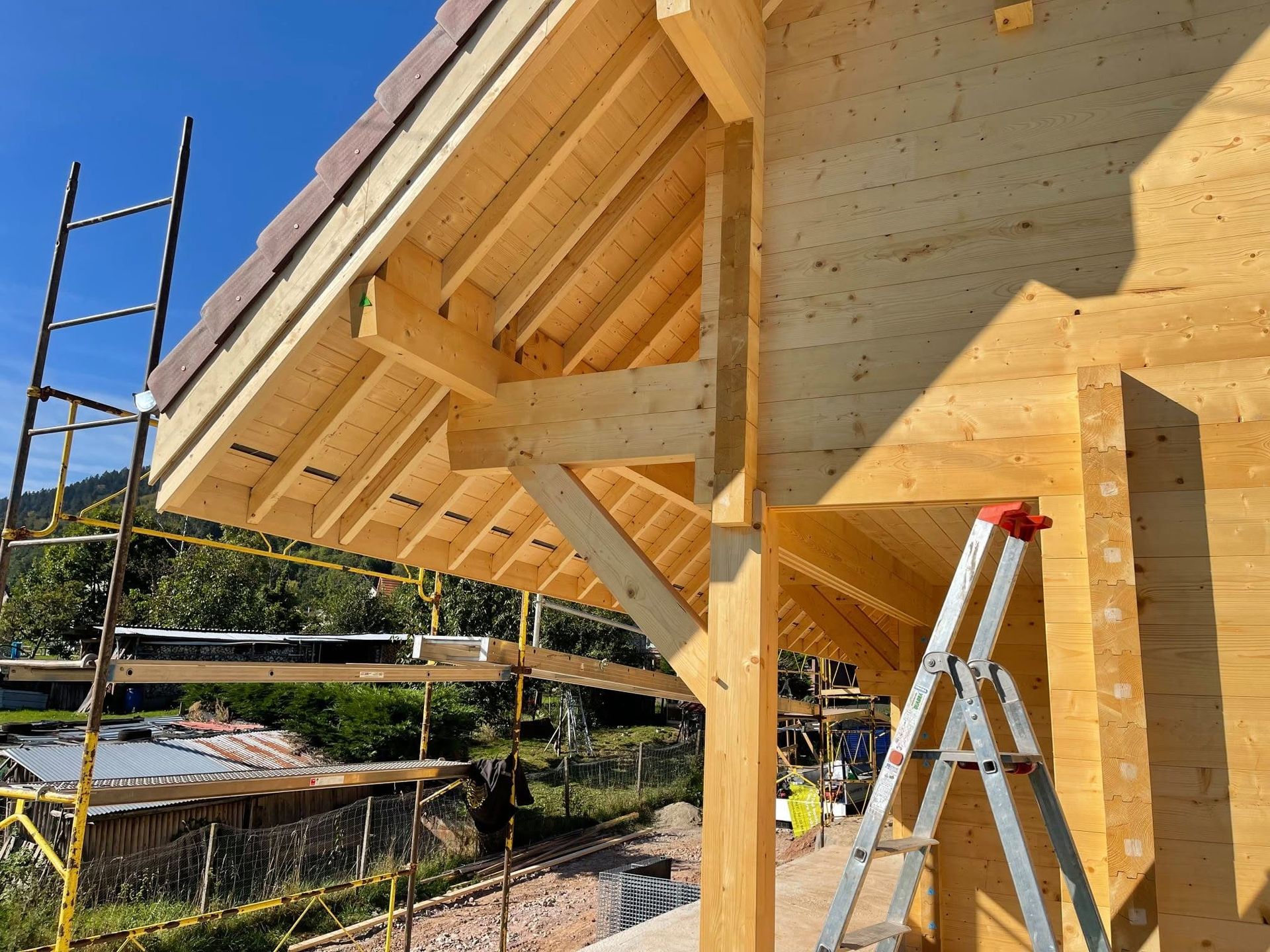 Gros plan sur un dessous de toiture d'une maison à ossature en bois en construction, avec échelles et échafaudages.