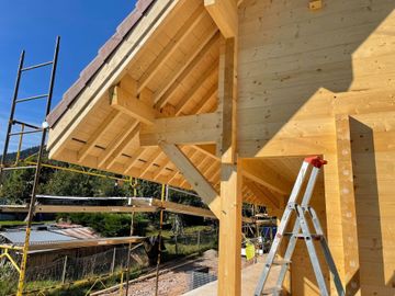 Gros plan sur un dessous de toiture d'une maison à ossature en bois en construction, avec échelles et échafaudages.