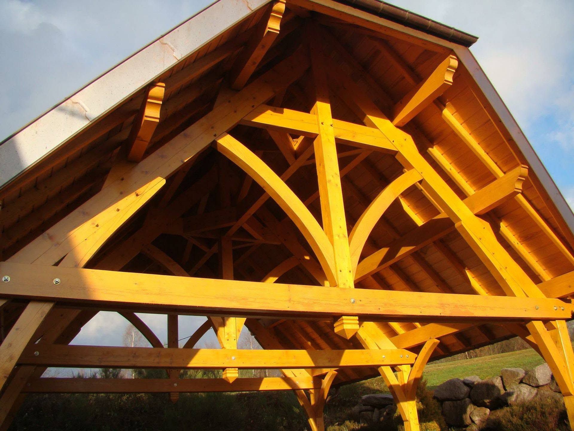Toit d'un pavillon en bois avec poutres apparentes d'une charpente traditionnelle.