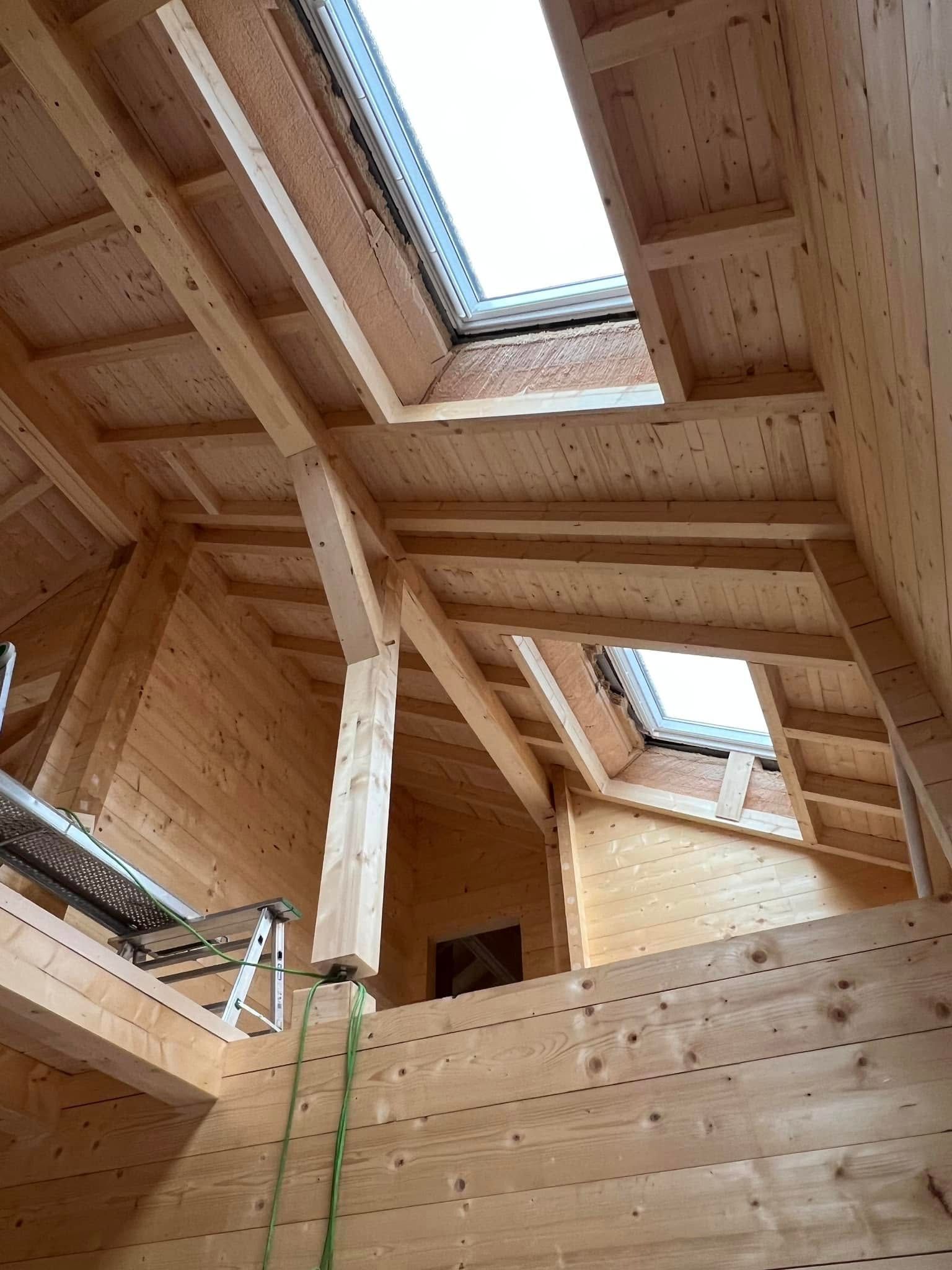 Intérieur en bois avec poutres apparentes et des fenêtres de toit.