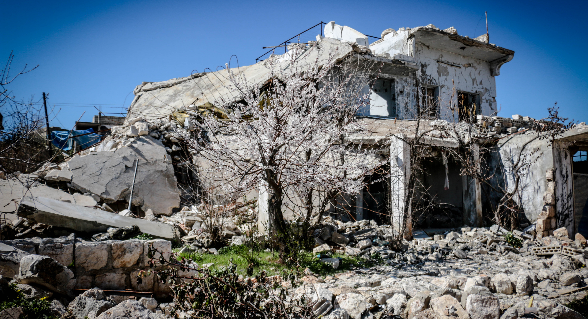 Excavatrice jaune démolissant un bâtiment, décombres et débris au premier plan.