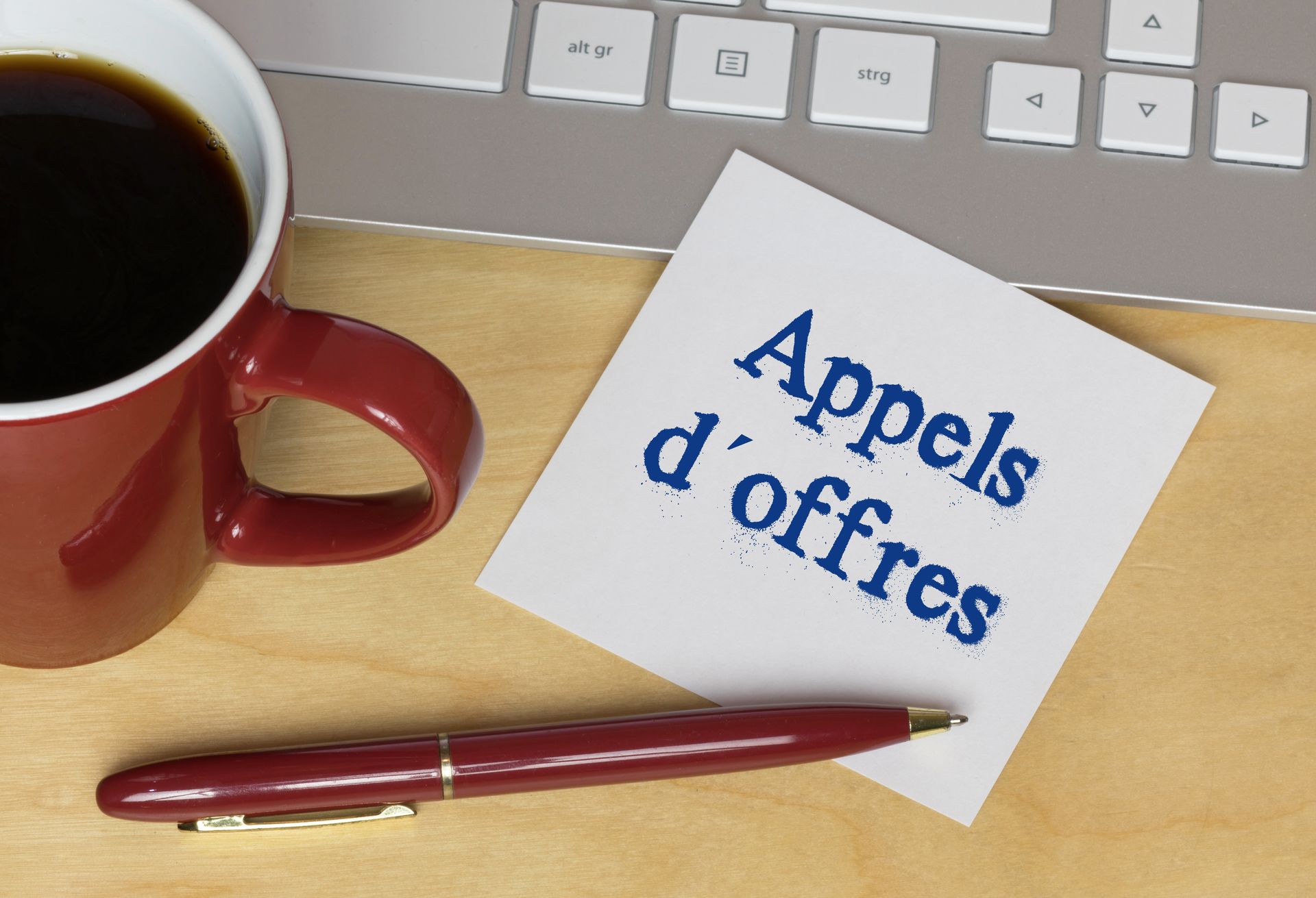 Un post it, un clavier, un stylo et une tasse.
